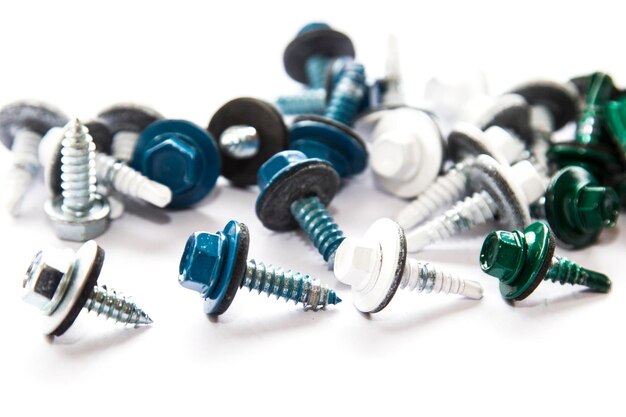 Screws of metallic, white, blue and green colors mixed on white background