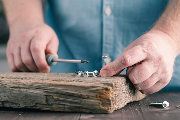 Screws on wood in male hands