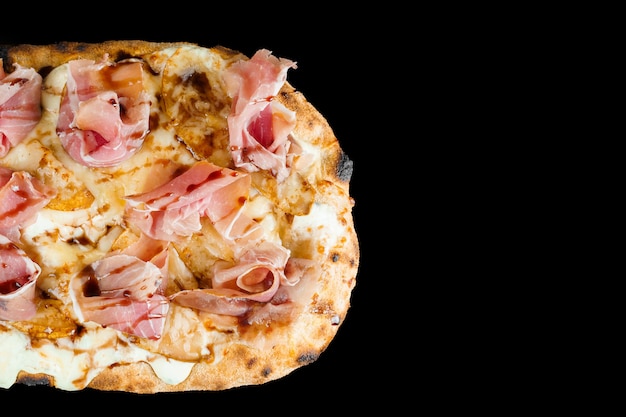 Scrocchiarella with pear, cheese, prosciutto on black background. Pinsa romana gourmet italian cuisine.Junk food.