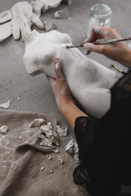 Sculptor paints the statuette with a brush