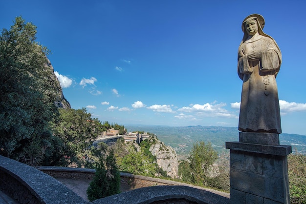 Sculpture of a of stone on the background of the abbey of Santa Maria de Montserrat in the mountains of Montserrat. Barcelona, Catalonia, Spain