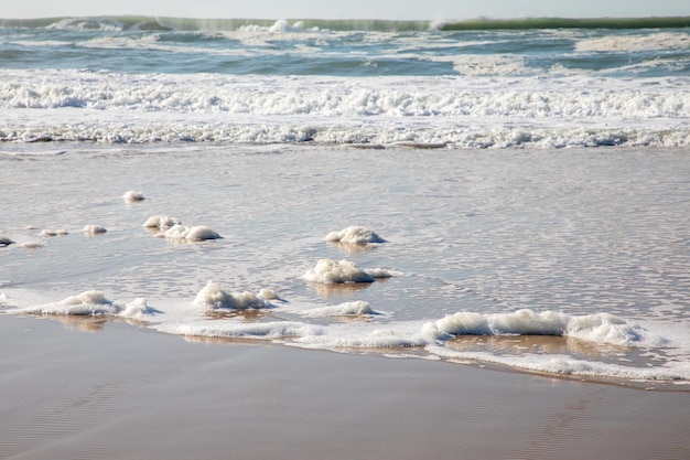 Scum sea water soft ocean wave on the sandy beach background