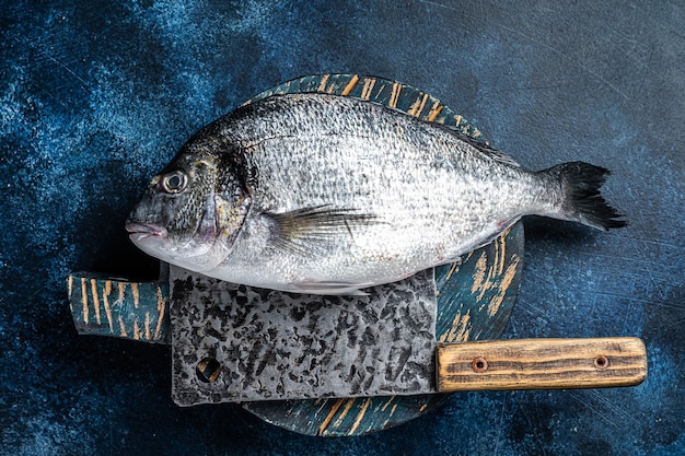 Sea bream or dorado fish on fish market cutting board Blue background Top view