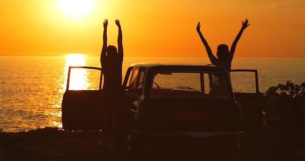 The sea brings out their inner little girls Rearview shot of two unrecognizable girl friends cheering with their arms raised while on a road trip at the beach