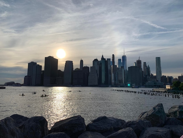 Photo sea by buildings against sky during sunset