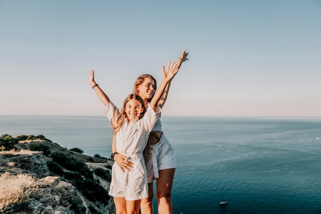 Sea family vacation together happy mom and teenage daughter hugging and smiling together over sunset