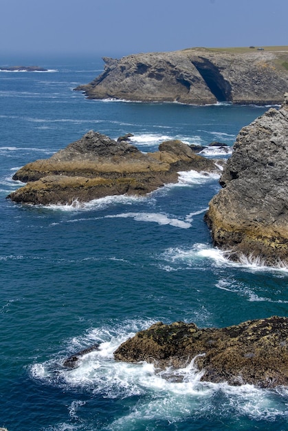 The sea is blue the waves break on the rocks and the tormented cliffs on the coast of BelleIle