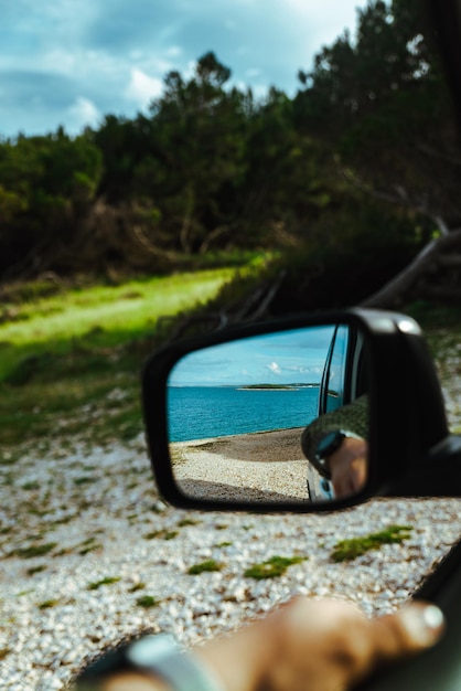 Sea reflection in car rear mirror road trip