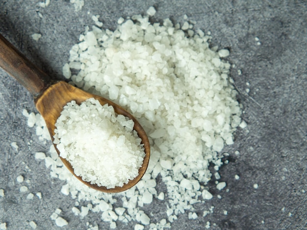 sea salt a pile of sea salt in a wooden spoon on a dark stone background closeup