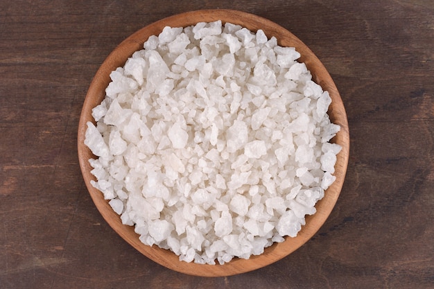 Sea salt in a wooden bowl on a wooden background