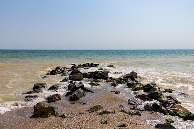 Sea seaside with stones, Waves clean blue water and blue sky on the background. Coast of beautiful summer sea. Traveling and vacations season.