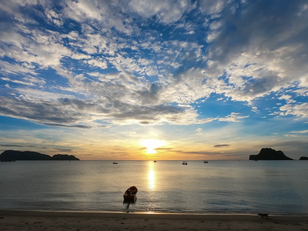 sea in summer season during the morning sunrise with small boat and cloudy sky.