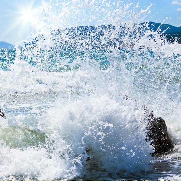 Sea surf wave break on coastline and Meganom cape on horizon right (Crimea, Ukraine)