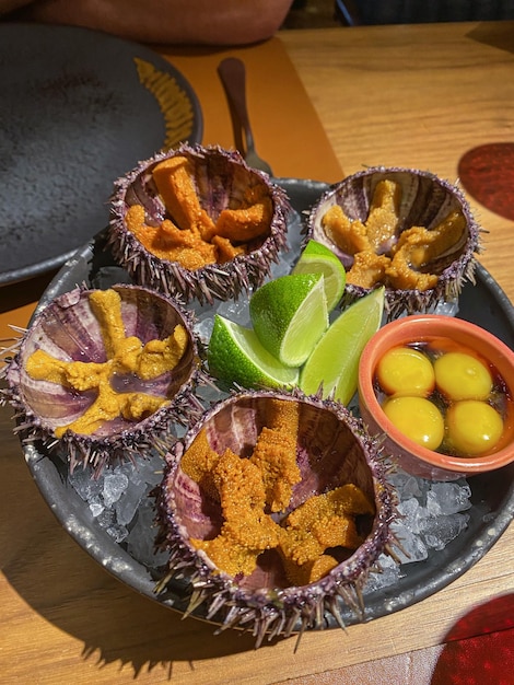 Sea urchin hedgehog with lime and quail eggs serviced in ice on a plate in a seafood bar