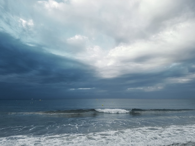 Sea view with traveling waves against the background of a dark sky with cumulus clouds.