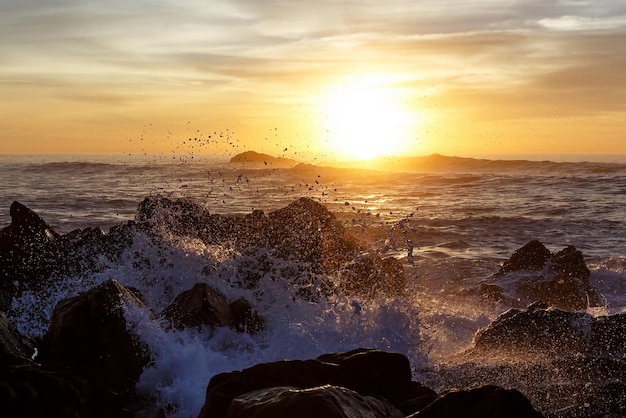 Sea waves crashing onto the rocks on sunset