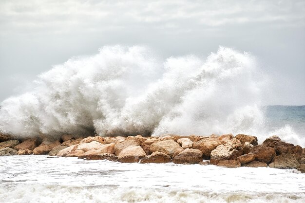 Sea waves crashing strongly against a breakwater near the shore of the beach on a day of rough seas and bad weather