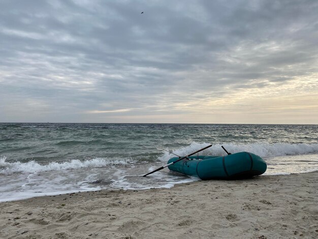 Sea waves crushing on abandoned inflatable boad on the seashore