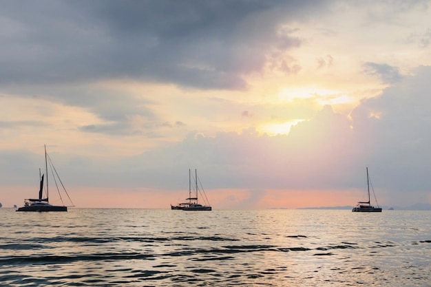 Sea with silhouettes of various boats against a sunset sky