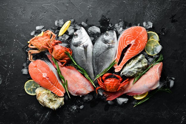 Seafood Dorado salmon crab grouper oysters On a black stone background Top view Free space for your text