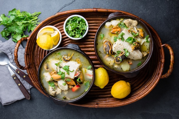 Seafood fish soup in clay bowls served with lemon and coriander. 