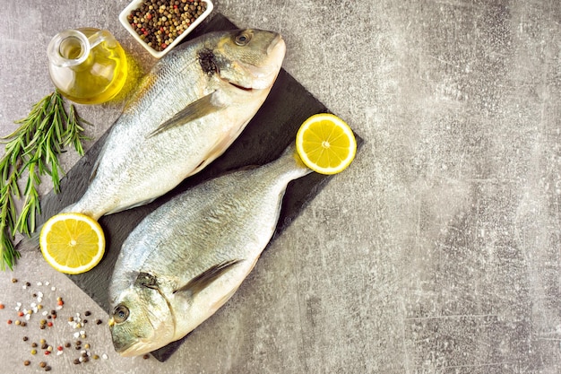 Seafood fresh fish dorado and ingredients for cooking on gray background Top view with copy space