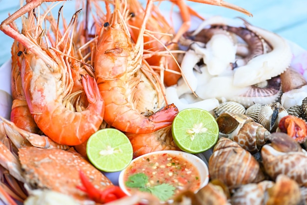 Seafood plate with shrimp shellfish crab squid cockle spotted babylon with seafood sauce chili lemon lime serve on dining table shrimps prawns seafood buffet menu cooked food