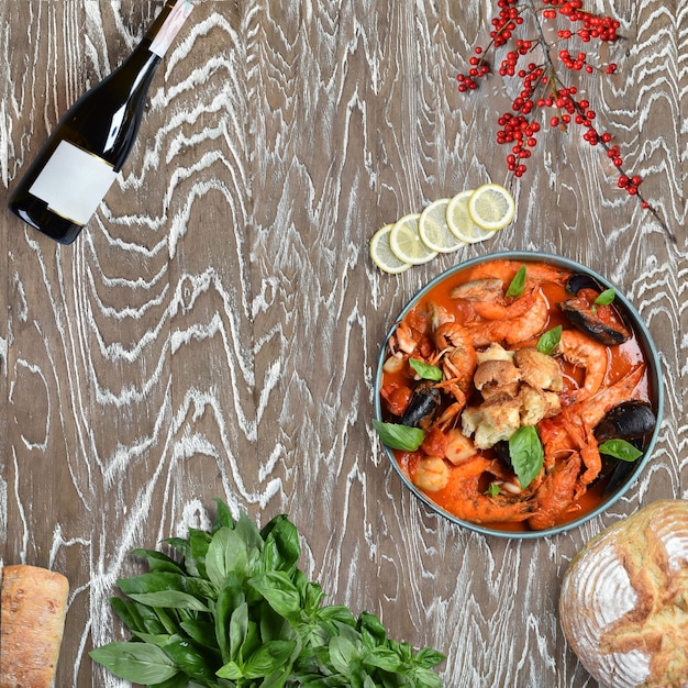 Seafood in tomato sauce with herbs. Shrimps, mussels, crayfish in red sauce on a wooden table