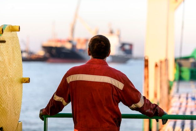 Seaman in red working overall and orange helmet on deck Working at sea Cargo vessel Mooring operations Able seaman