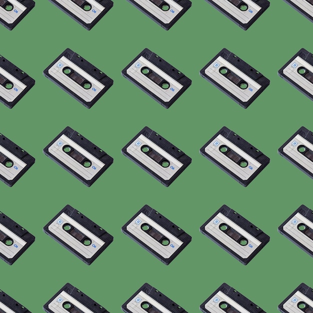 Seamless pattern of audio cassettes on a green background Retro gadgets