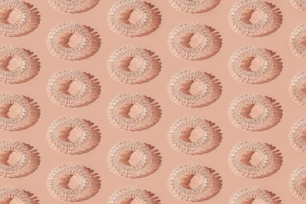 Seamless pattern made of transparent spiral silicone hair scrunchie thing Woman beauty accessory Pastel pink background