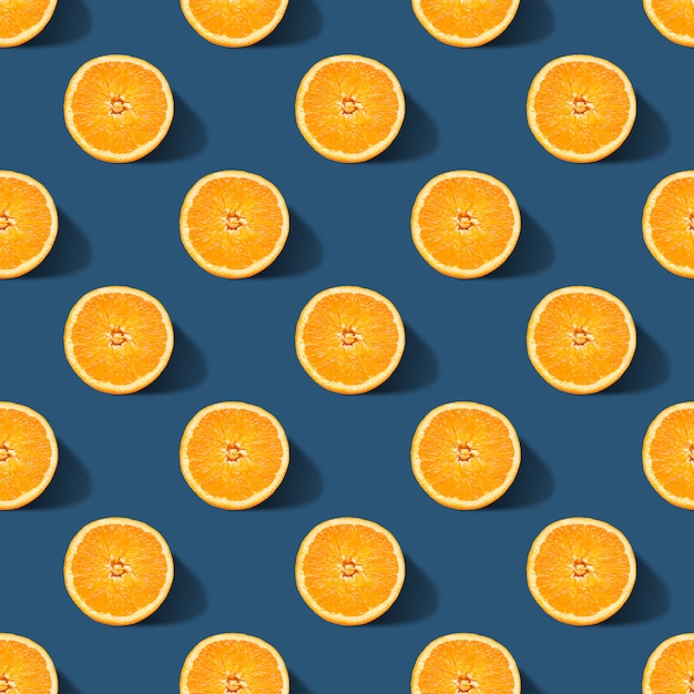 Seamless pattern of orange sliced on classic blue color background. Minimal, flat lay.