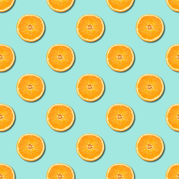 Seamless pattern of orange sliced on neo mint green color background. Minimal, flat lay.