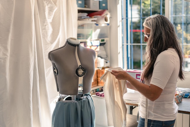 Seamstress checking a piece of fabric to put it on a mannequin