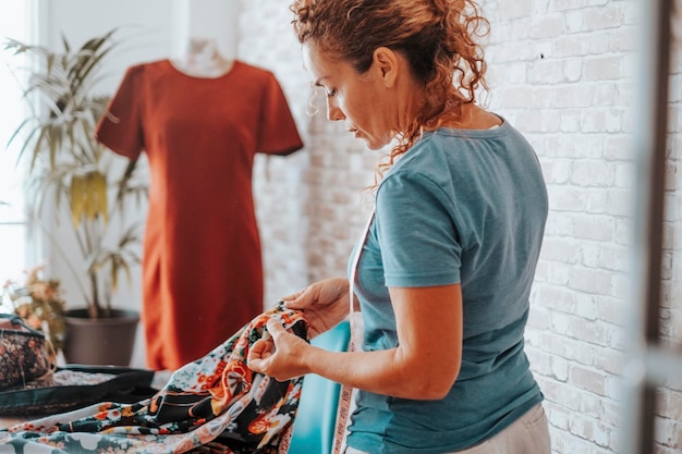 Seamstress at home workshop working with clothes in fashion industry Professional tailor making dress Side view of woman in hobby and leisure activity indoor alone Concept of alternative job life