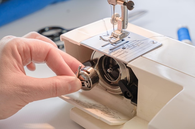 Seamstress pulling bobbin of an electric sewing machine