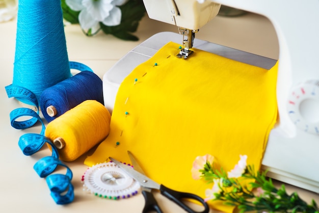 Seamstress's workplace. Professional sewing machine at work. Sewing machine sews bright textiles, meter and colored threads for sewing