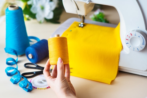 Seamstress's workplace. Professional sewing machine at work. Sewing machine sews bright textiles, meter and colored threads for sewing