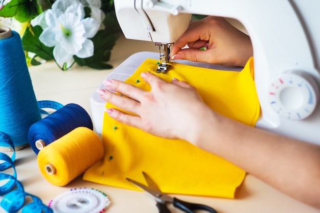 Seamstress's workplace. Professional sewing machine at work. Sewing machine sews bright textiles, meter and colored threads for sewing