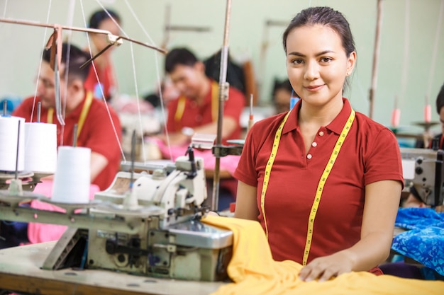 Seamstress in textile factory smiling while sewing