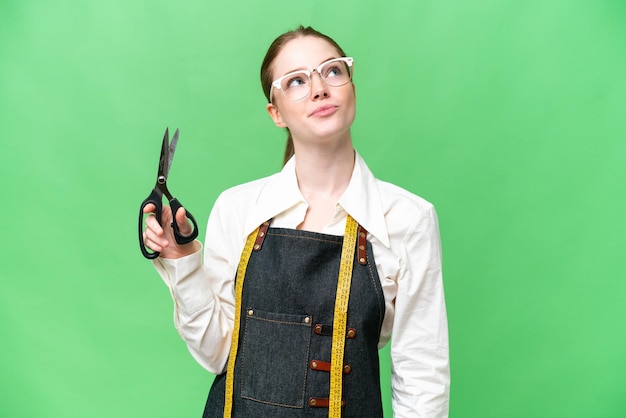 Seamstress woman over isolated chroma key background and looking up