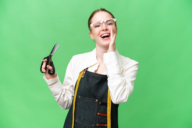 Seamstress woman over isolated chroma key background shouting with mouth wide open