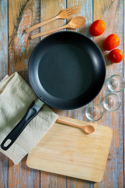 Search by image Cast iron pan and other kitchen utensils on a dark brown aged background top view