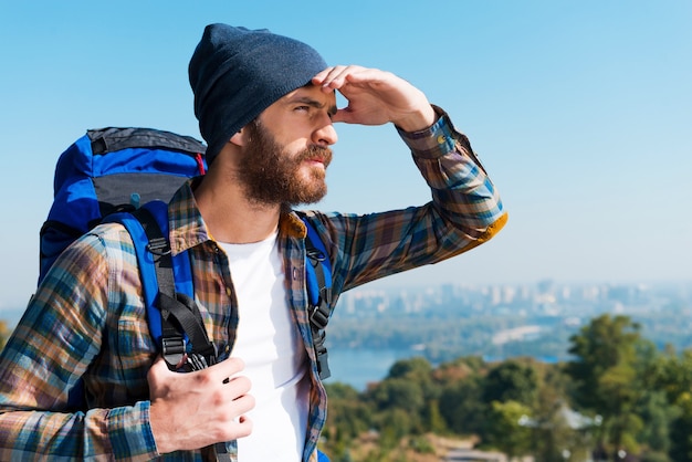 In search of new horizons. Handsome young man carrying backpack and looking away