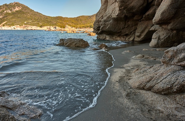 Seascape featuring a natural cave and a beach with crystal clear sea in the south of Sardinia

