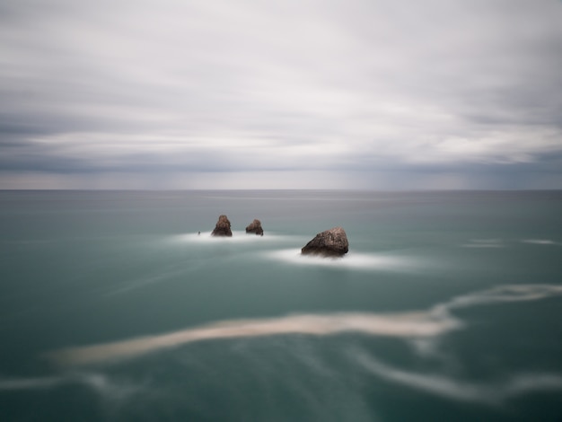 Seascape of lonely rocks in the ocean. Coastal sunrise. Wallpaper.