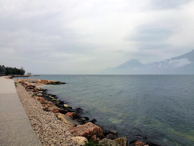 Seascape of rocky embankment and bay of cold sea near distant mountains