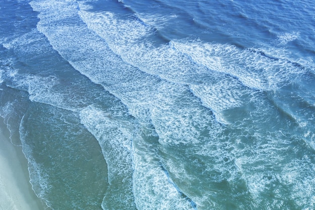 Seascape Sandy beach Sea waves roll onto the sandy beach Top diagonal view Abstract nature landscape background