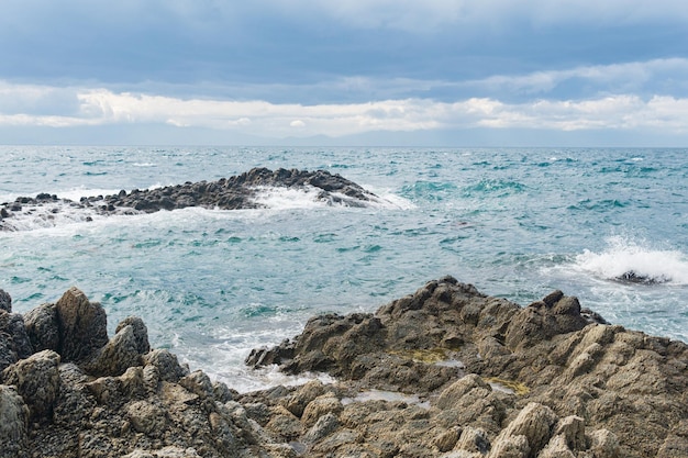 Seascape with distant wooded shore on a background and rocks in the surf on a foreground Kunashir island landscape