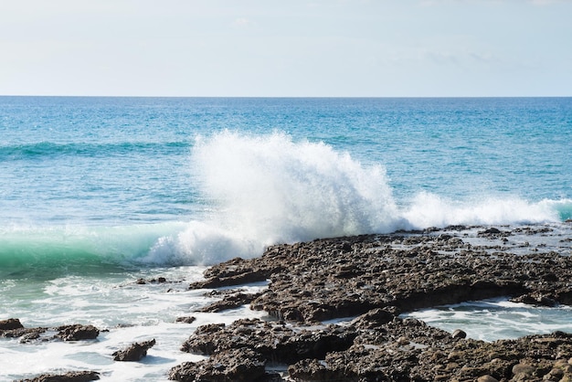 Seascape with rocky shore surf waves and bright sky